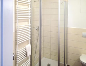 A bathroom with a glass-enclosed shower, a white towel rack, and a toilet.