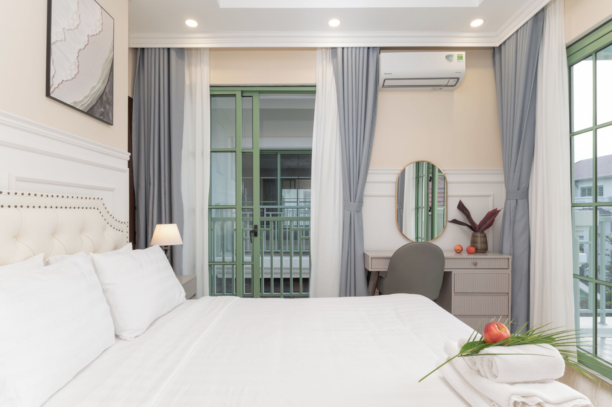 A hotel room with a bed, a desk, a mirror, and a window with curtains.