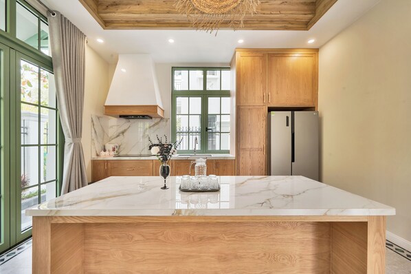 A kitchen with a marble countertop, wooden cabinets, and a large window.