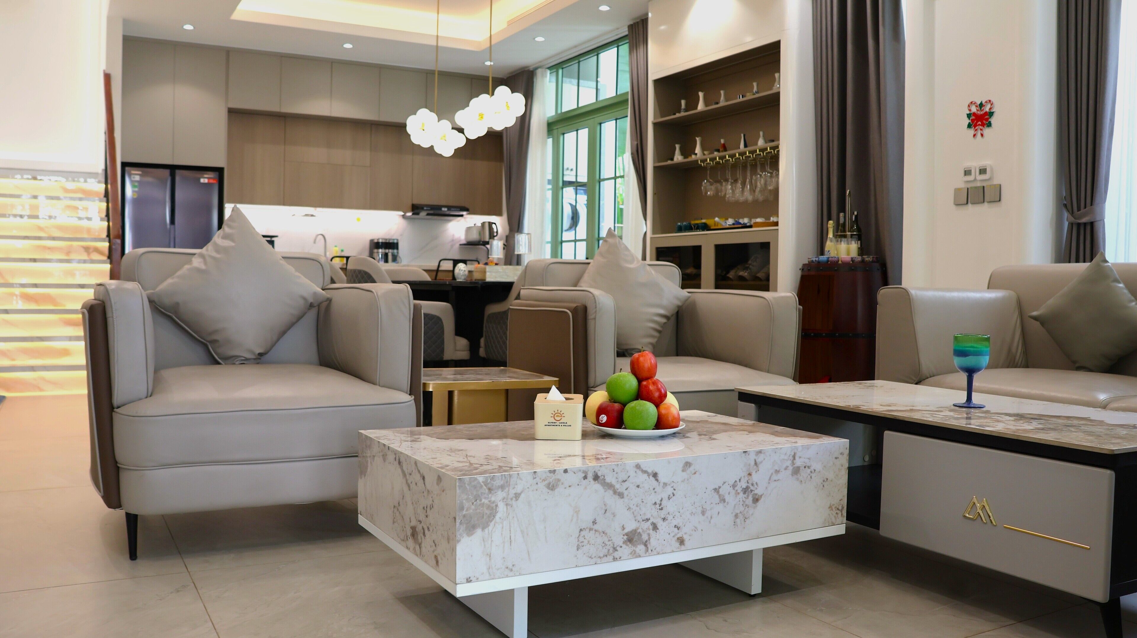 A modern living room with a marble coffee table, a sofa, and a dining area with a kitchen in the background.