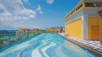 Relax by the infinity pool with a striking blue mosaic design, surrounded by a spacious deck with a patterned floor.