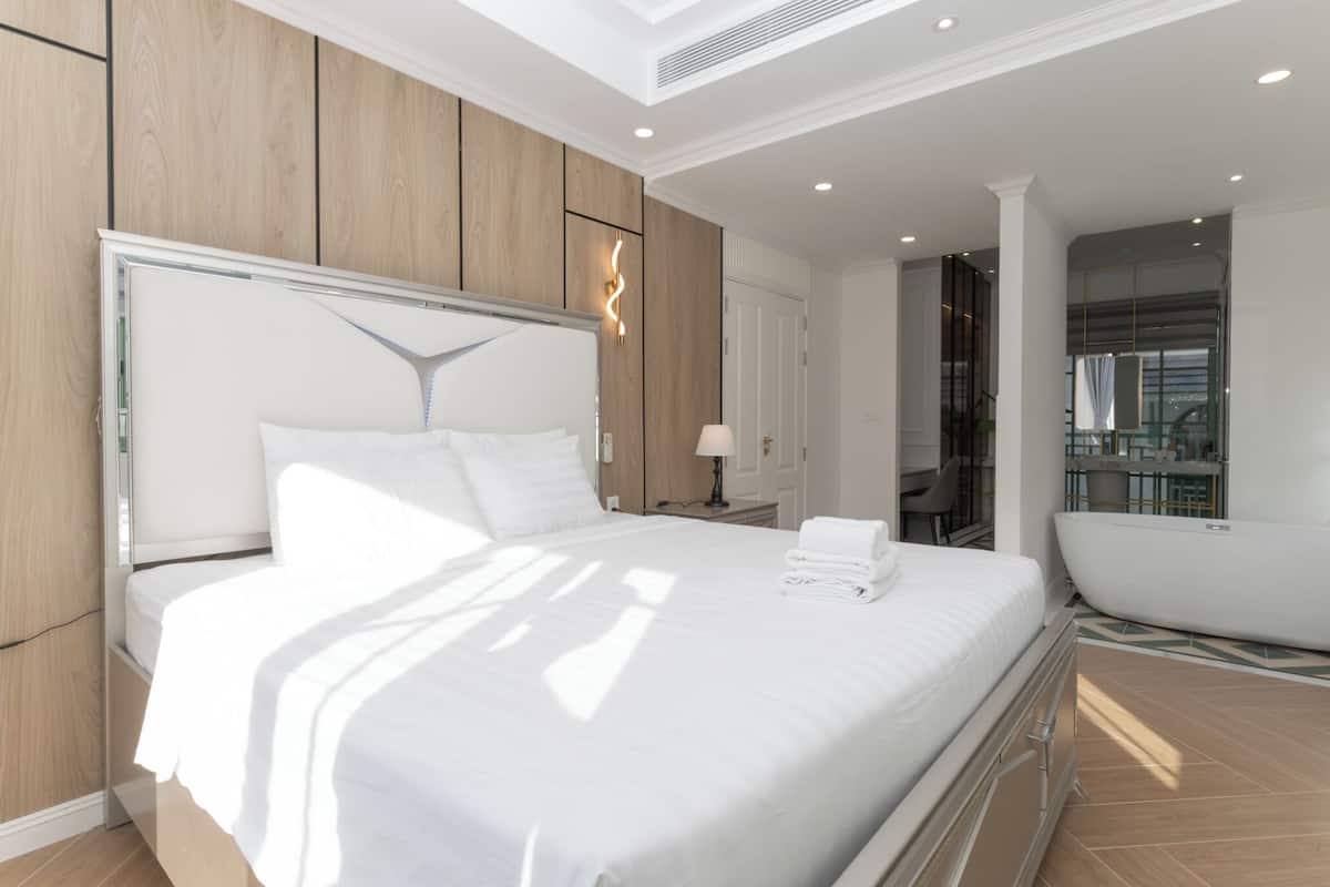 A modern hotel room with a large bed, a bathroom with a bathtub, and a view of the city.
