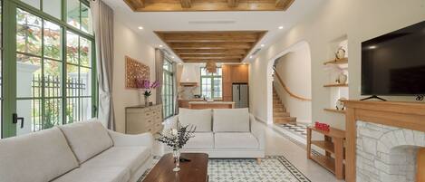 A spacious living room with a wooden ceiling, a sofa, a coffee table, and a fireplace.