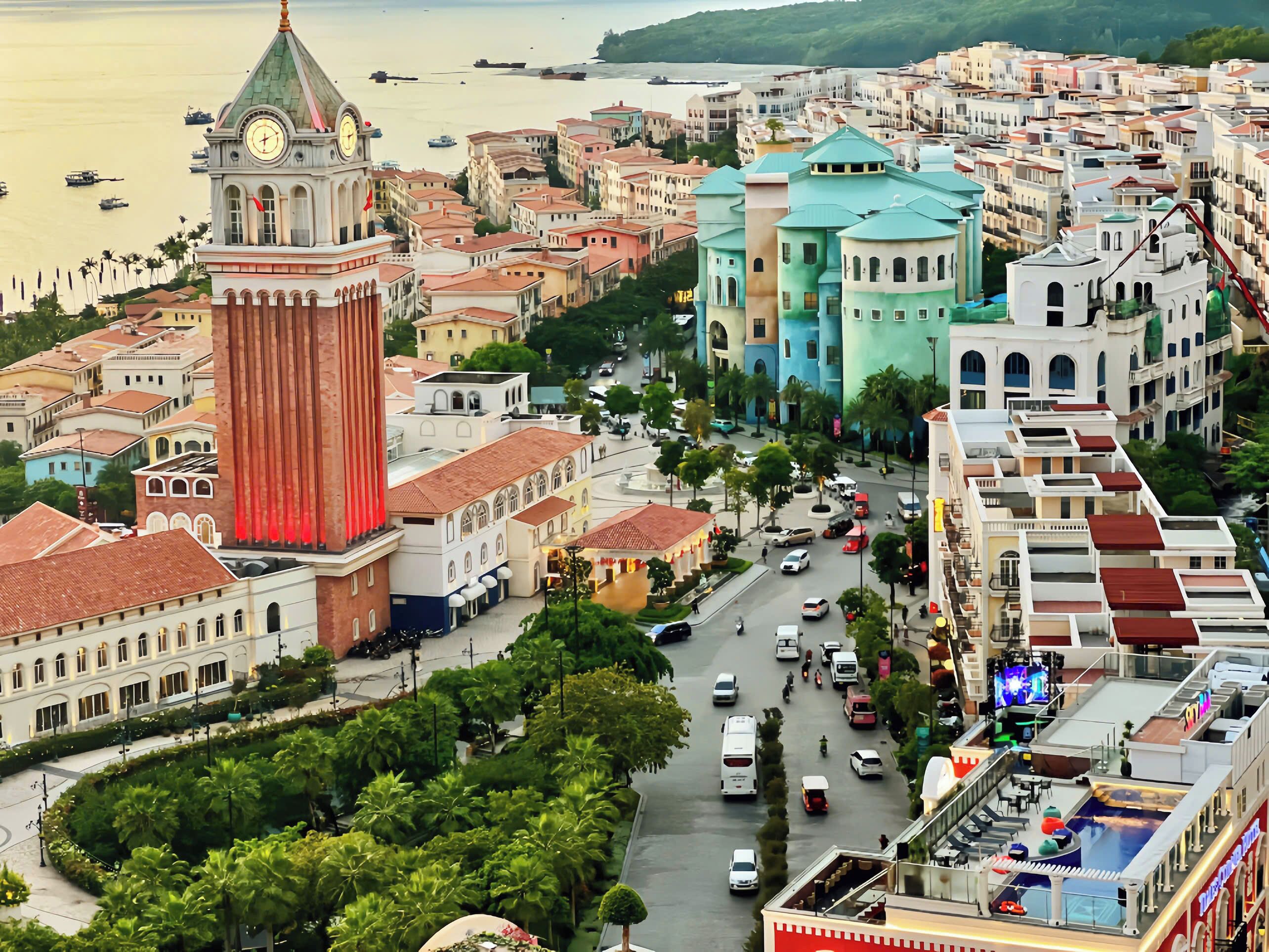 A coastal cityscape with a prominent clock tower, a busy street, and a variety of colorful buildings.