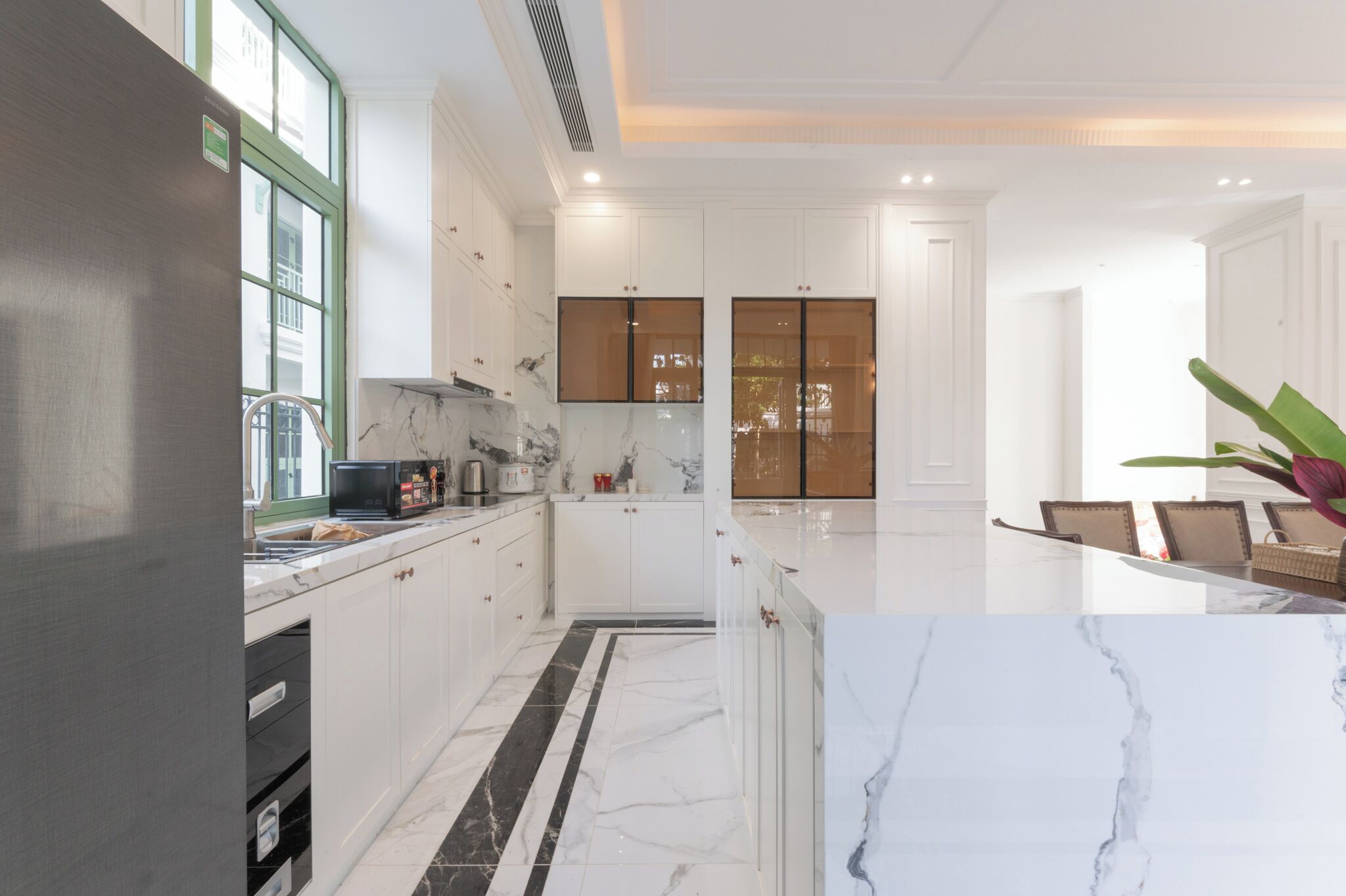 Une cuisine moderne avec des meubles blancs, un plan de travail en marbre et un sol à rayures noires et blanches.