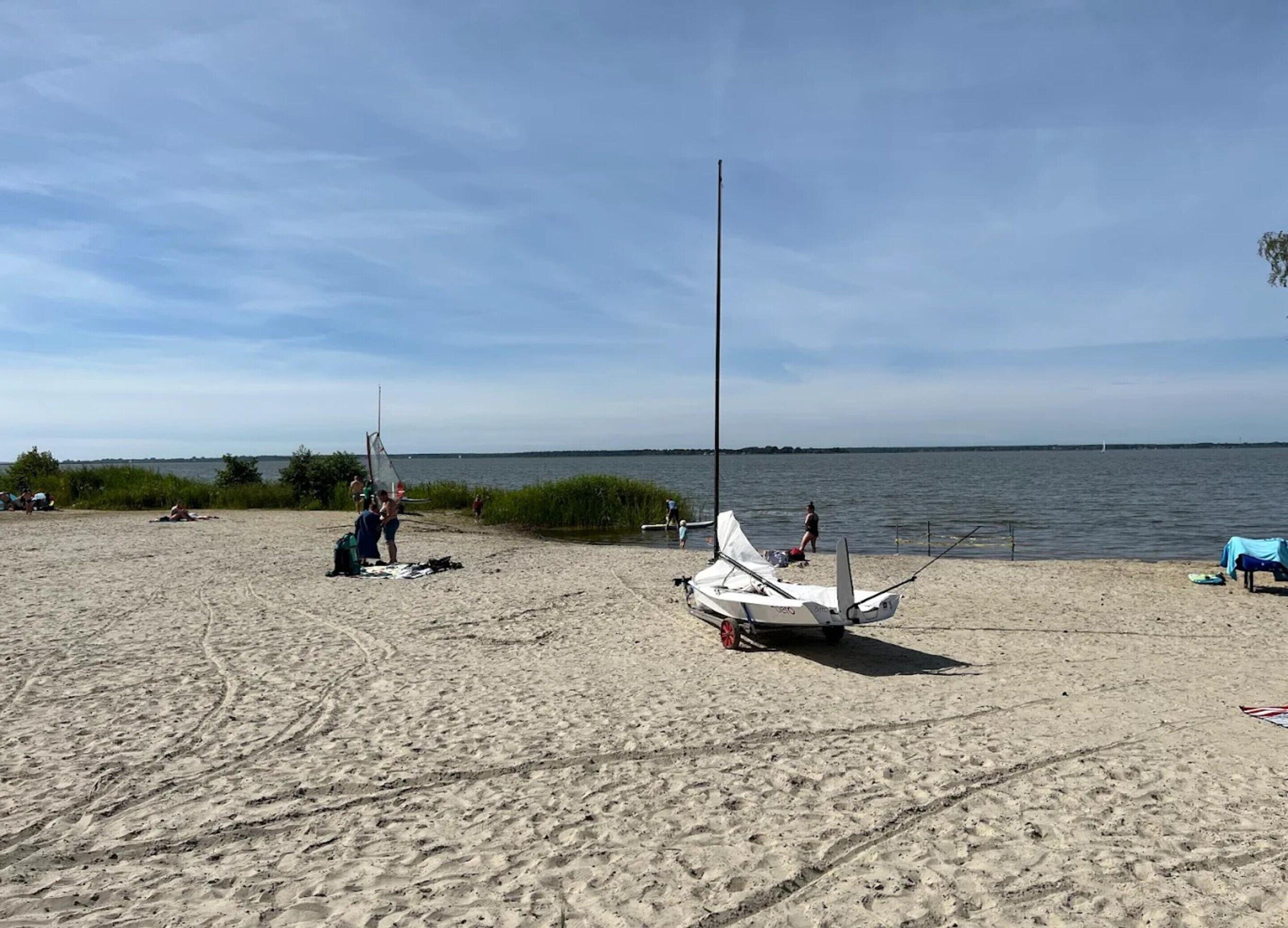 A sandy beach with a sailboat and a small boat.