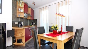 A compact kitchen with modern appliances, a dining table with four chairs, and a red placemat. - Doppelhaushaelfte am Hafen von Neuendorf (Saal)