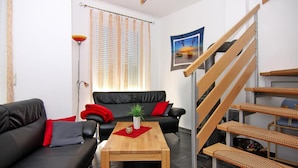 A modern living room with a black leather sofa, a wooden coffee table, and a staircase with woven steps. - Doppelhaushaelfte am Hafen von Neuendorf (Saal)