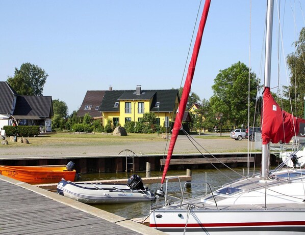 A marina with boats docked, a yellow house in the background, and a clear sky. - Doppelhaushaelfte am Hafen von Neuendorf (Saal)