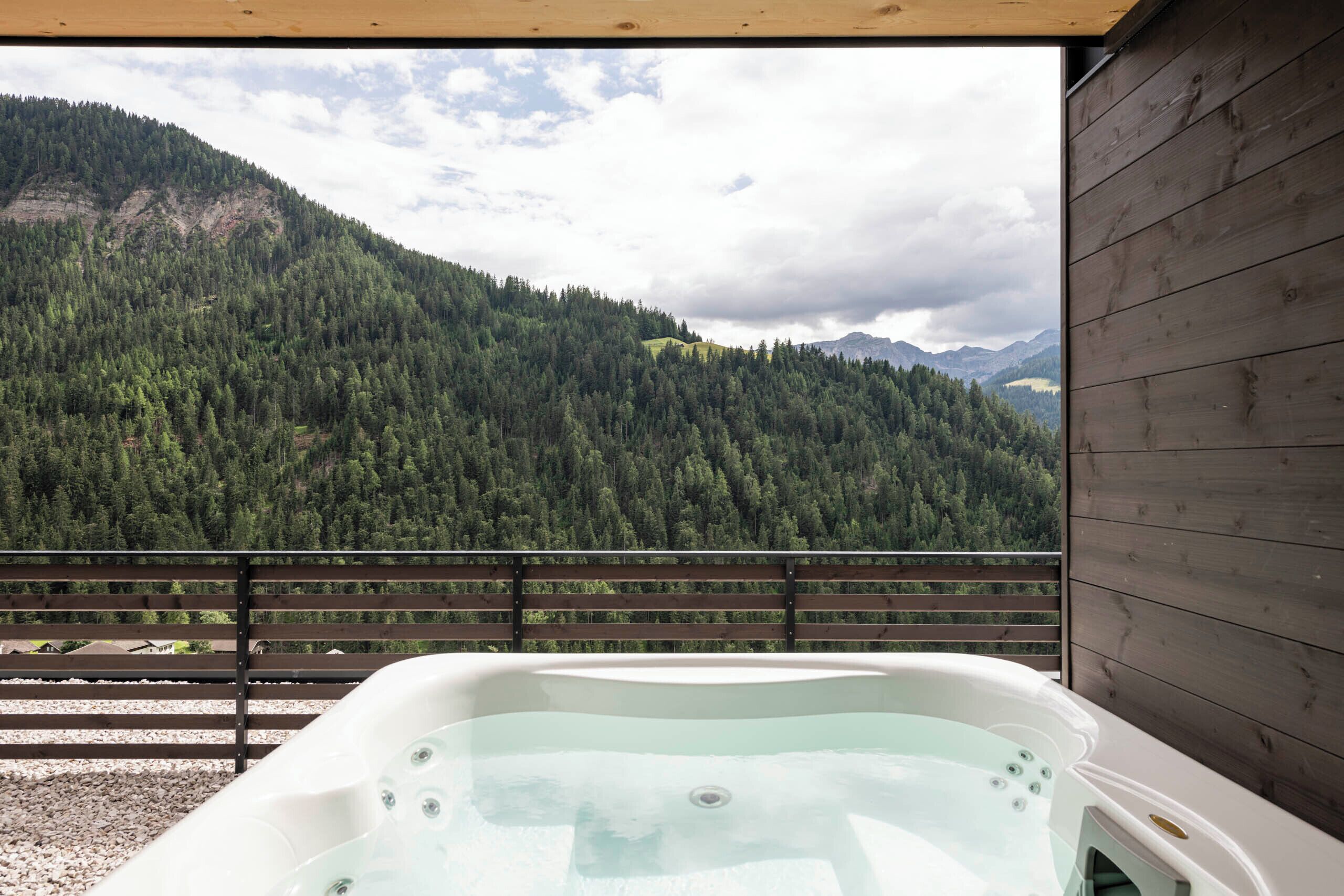 Ein Whirlpool auf einem Balkon mit Blick auf einen bewaldeten Berg.
