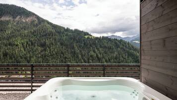 Ein Whirlpool auf einem Balkon mit Blick auf einen bewaldeten Berg.