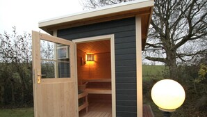 A small wooden cabin with a door open, revealing a bench inside. - Ferienhaus Wiesengrund mit Sauna, Dornumersiel (Dornum)