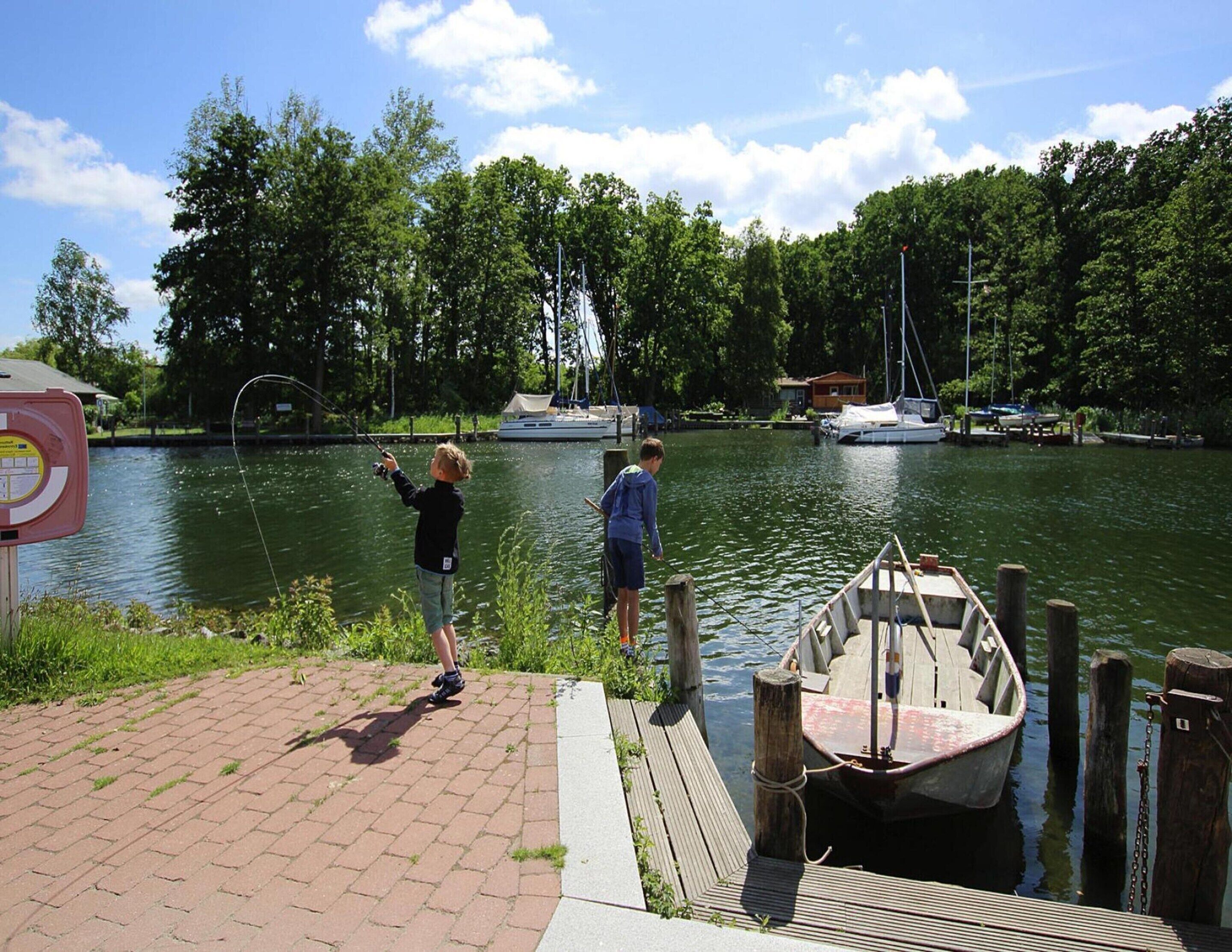 A dock with a boat, a wooden pier, and a calm water body with boats in the background.