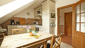 A kitchen with a dining area, wooden cabinets, a microwave, and a clock on the wall. - Apartment, Kenz-kustrow (Kenz-Küstrow)