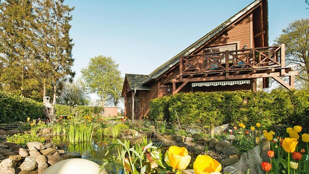 A wooden cabin with a deck, surrounded by a garden with a pond and tulips. - Apartment, Kenz-kustrow (Kenz-Küstrow)
