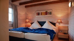 Un dormitorio de cabaña de madera acogedor, con una cama doble, dos lámparas de noche y una obra enmarcada en la pared.