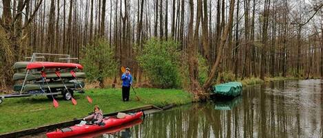 A calm river with a red canoe and a green boat docked on the bank.