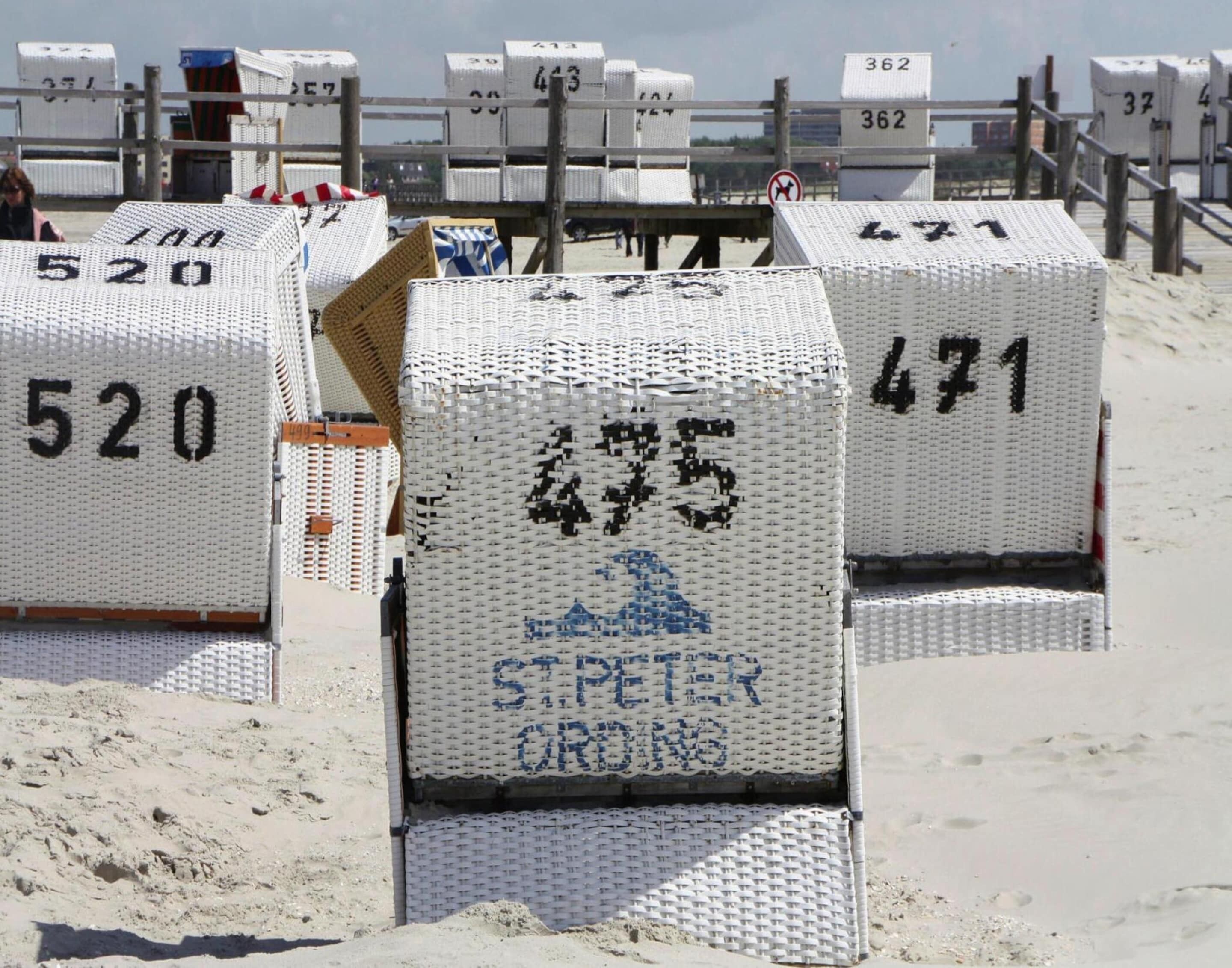 Beachside numbered beach huts with a sign indicating 'ST. PETER DRUMS'.