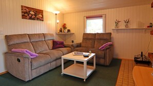 A living room with two sofas, a small white table, and a window with blinds. - Ferienhaus in Hunning an der Treene (Silberstedt)