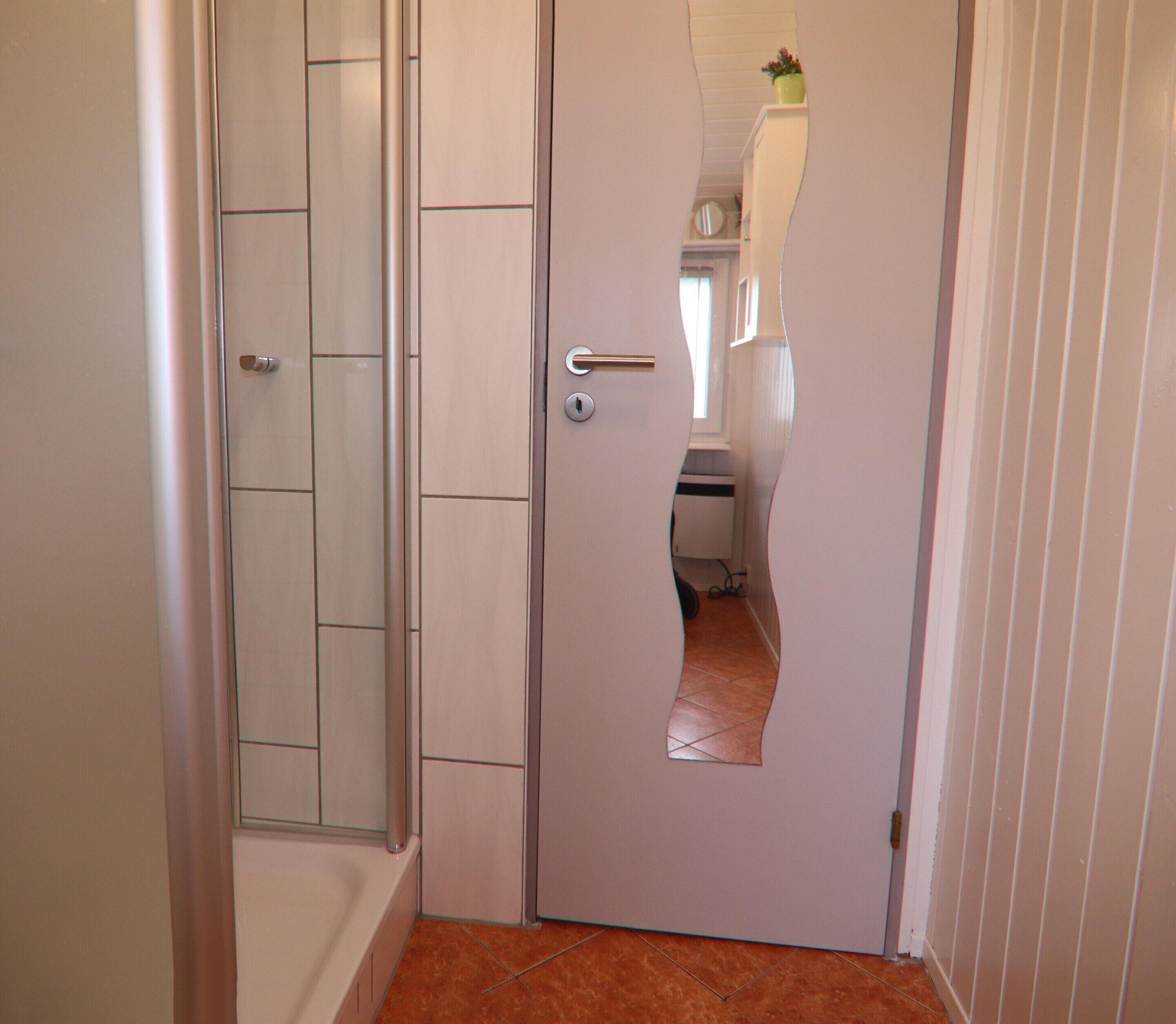 A narrow hallway with a door featuring a large, irregularly shaped cutout.