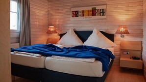 Habitació acollidora amb un llit, dues làmpades de nit, una finestra amb cortines i un quadre penjat a la paret.