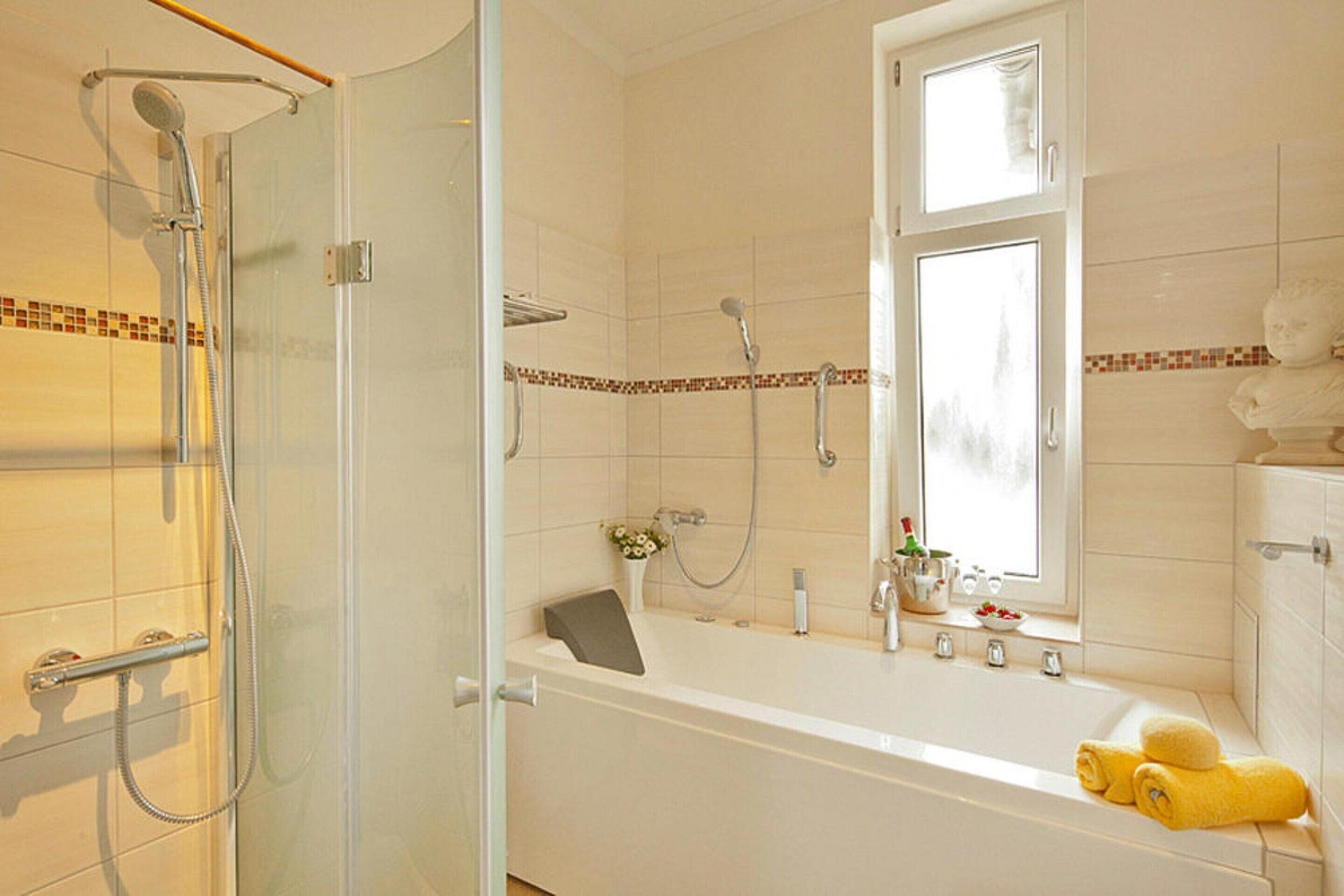 Een badkamer met douche, bad en een raam.