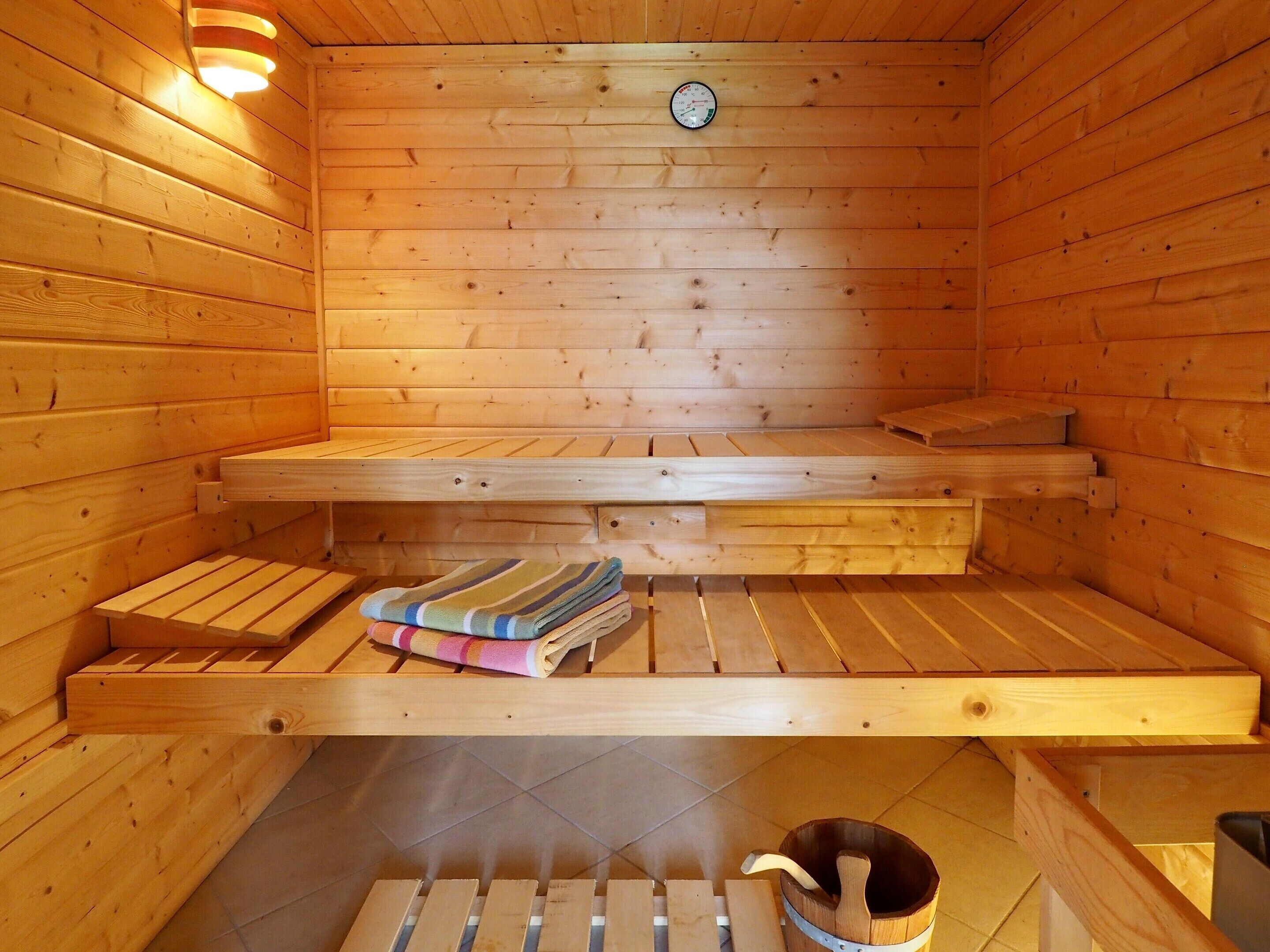 A wooden sauna with benches, a towel, and a bucket.