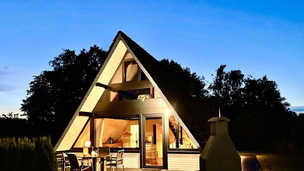 Un bâtiment de forme triangulaire doté d’un patio, d’une table à manger et de chaises.