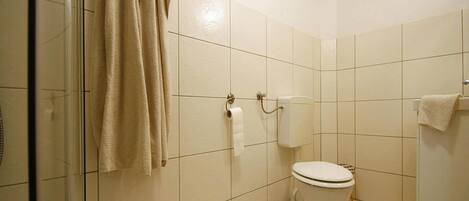 Et badeværelse med toilet, bruser og glasdør.