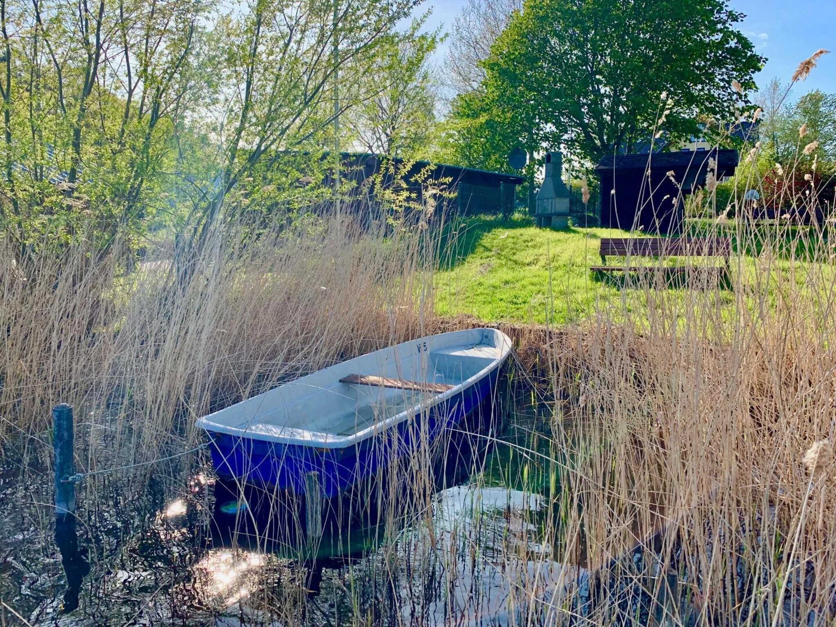 A boat in a garden with tall grass and trees.