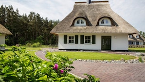 A traditional thatched-roof house with a white exterior, a green door, and a paved pathway leading to it. - Ferienhaus, Fuhlendorf (Fuhlendorf)