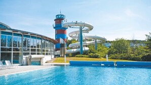 A swimming pool with a water slide and a building with large windows.