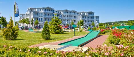 A hotel with multiple balconies, a green lawn, and a playground area.