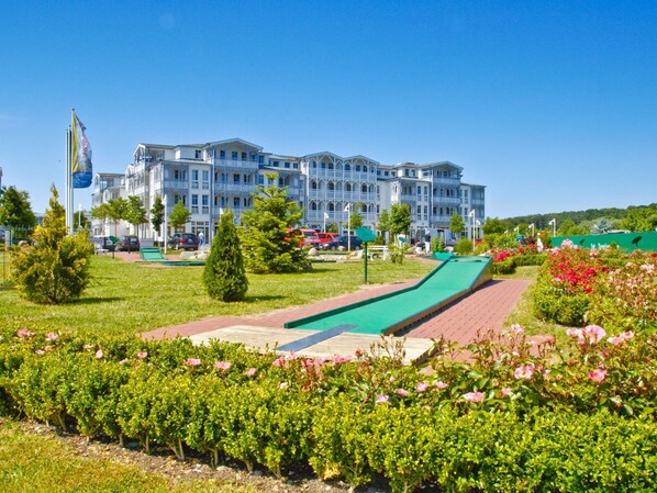 A hotel with multiple balconies, a green lawn, and a playground area.