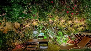 An outdoor seating area with a table and chairs, surrounded by lush greenery and flowering plants. - Luxueux Haut de Villa 4 Pers à 30m de la Plage (Sainte-Maxime)