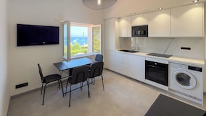 A modern kitchen with a dining area, built-in appliances, and a view of the sea. - Luxueux Haut de Villa 4 Pers à 30m de la Plage (Sainte-Maxime)