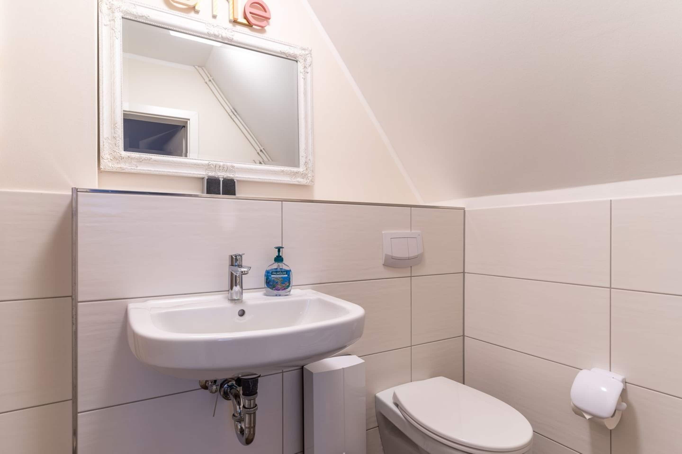 Un bagno con un lavandino bianco, uno specchio e un water.