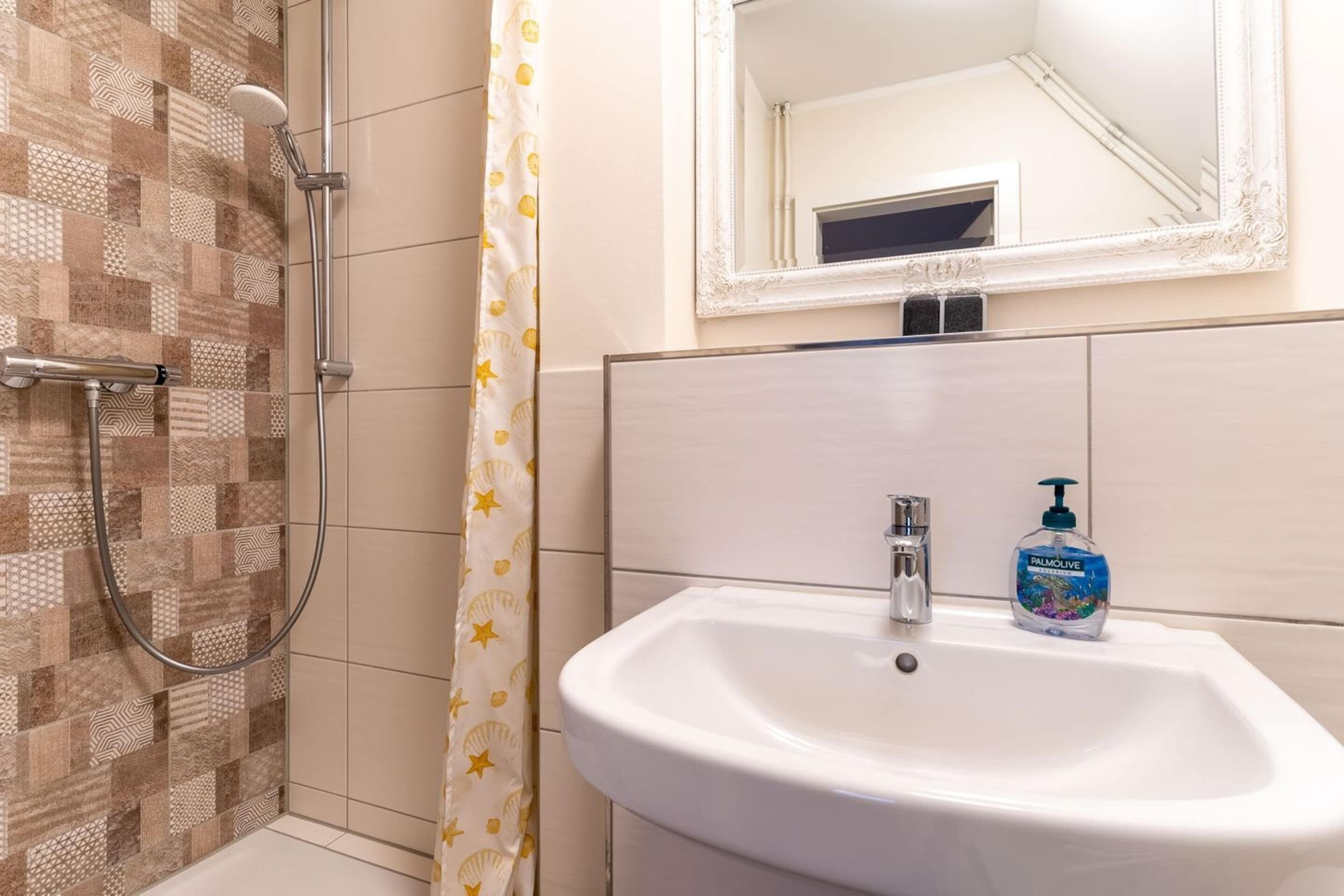 A bathroom with a shower, a sink, and a mirror.