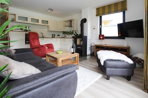 Una sala de estar moderna con un sofá, un sillón rojo, una mesa de centro y una chimenea.