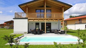 A two-story wooden house with a balcony, a swimming pool, and a garden. - Chalet Chiemgau, Inzell (Inzell)