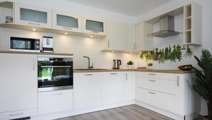 A modern kitchen with white cabinetry, a built-in oven, a microwave, and a coffee maker. - Chalet Chiemgau, Inzell (Inzell)