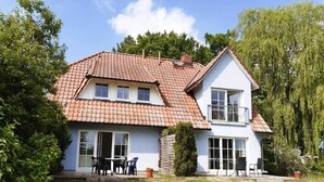 Een tweelaags huis met een pannendak, een balkon en een voortuin met tuinmeubilair.