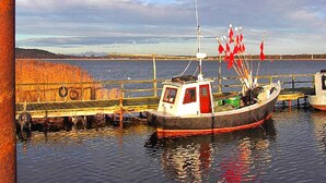 Un barco atracado en un muelle, con vista al agua y la costa distante.
