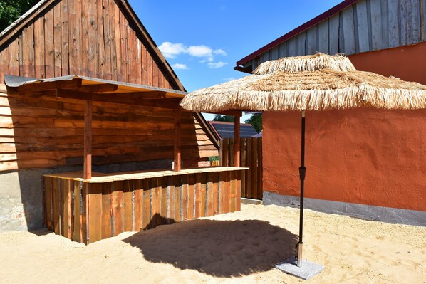 Une structure en bois avec un banc et un parasol en paille.