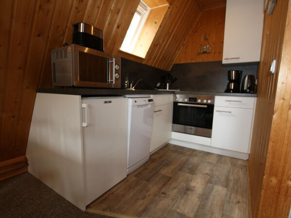 Een kleine keuken met een magnetron, oven, vaatwasser en spoelbak.