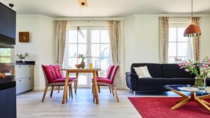 A modern living room with a dining area, a sofa, and a coffee table. - Ferienhaus, Fuhlendorf (Fuhlendorf)