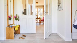 A hallway with a wooden bench, a mirror, and a door leading to a dining area. - Ferienhaus, Fuhlendorf (Fuhlendorf)