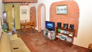 A living room with a television, speakers, and a bookshelf. There is a dining area with chairs and a table. - Holiday Home in Lucca Near Historic Walls (Lucca)