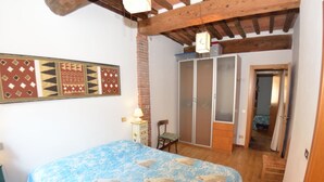 A bedroom with a bed, a wardrobe, a chair, and a lamp. - Holiday Home in Lucca Near Historic Walls (Lucca)