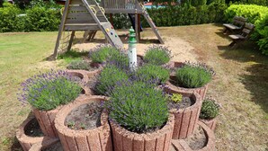 Un jardin agrémenté de jardinières circulaires en briques, dans lesquelles sont plantées des lavandes.